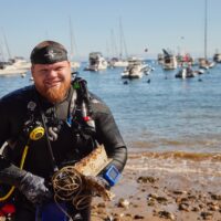 A diver exits the water with garbage found during a dive off Catalina Island, California