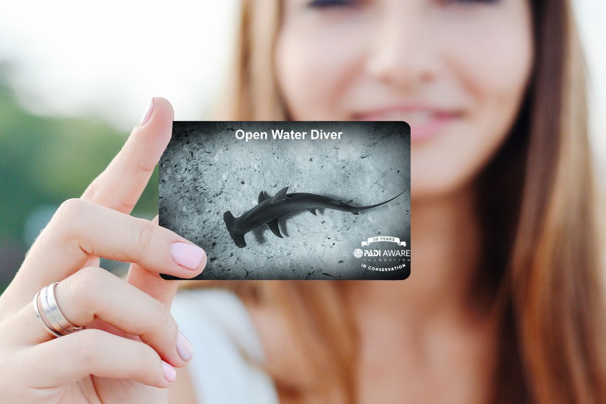 A diver holds up her padi replacement card gifts for scuba divers