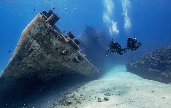 divers exploring a wreck on a sandy bottom