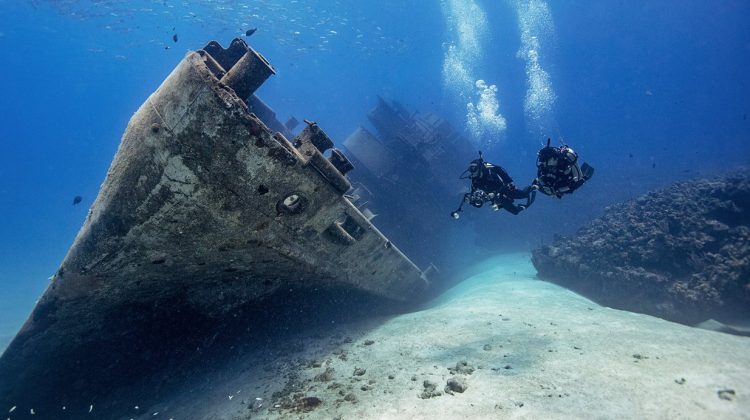divers exploring a wreck on a sandy bottom
