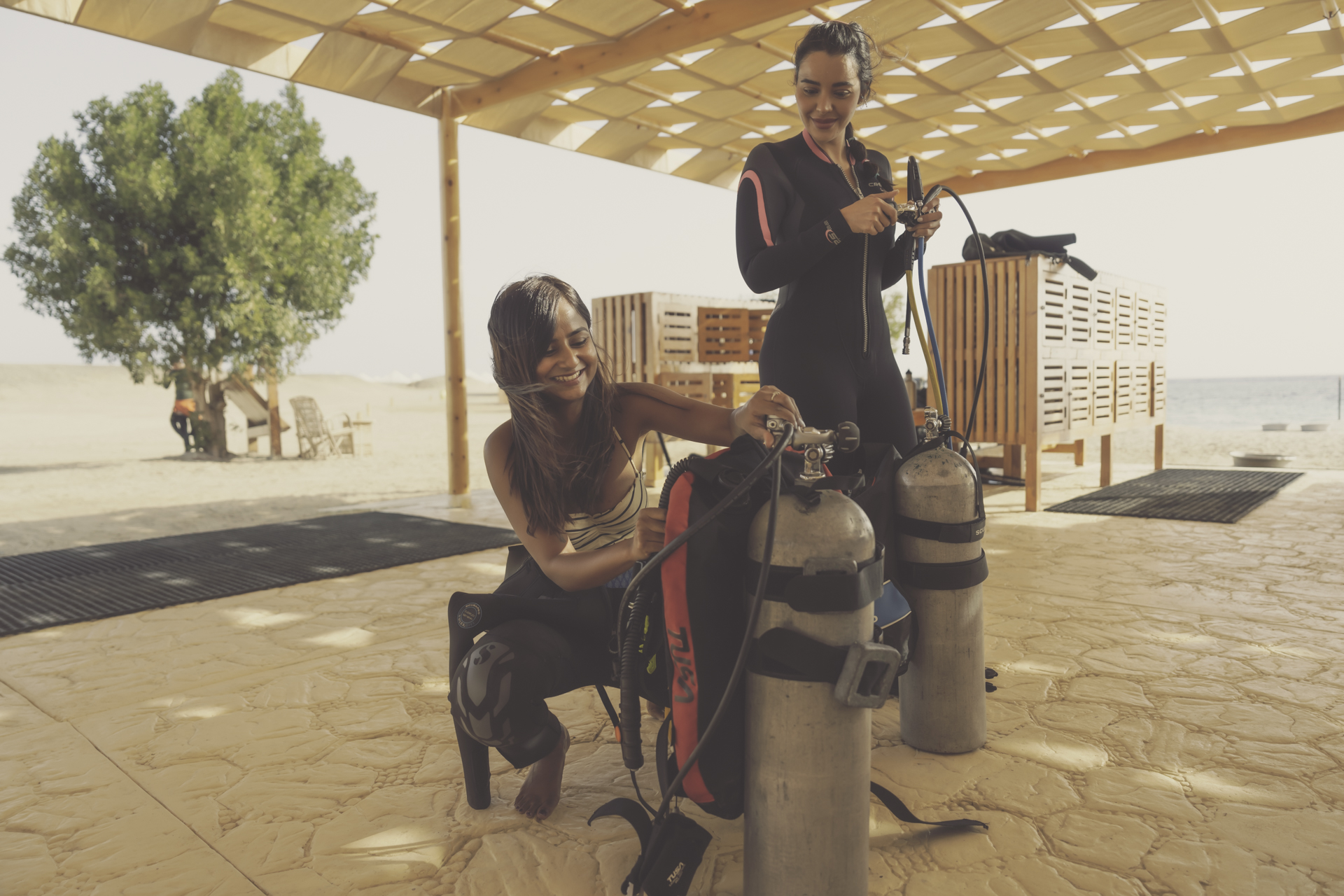 two female divers prepare their dive tanks and other dive gear for a shore dive in the Red Sea, Egypt