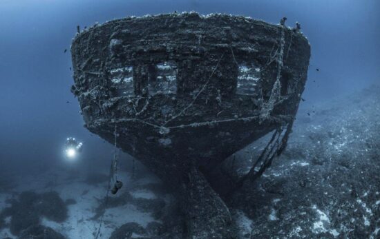a technical diver explores the stern of a sunken ship in Greece