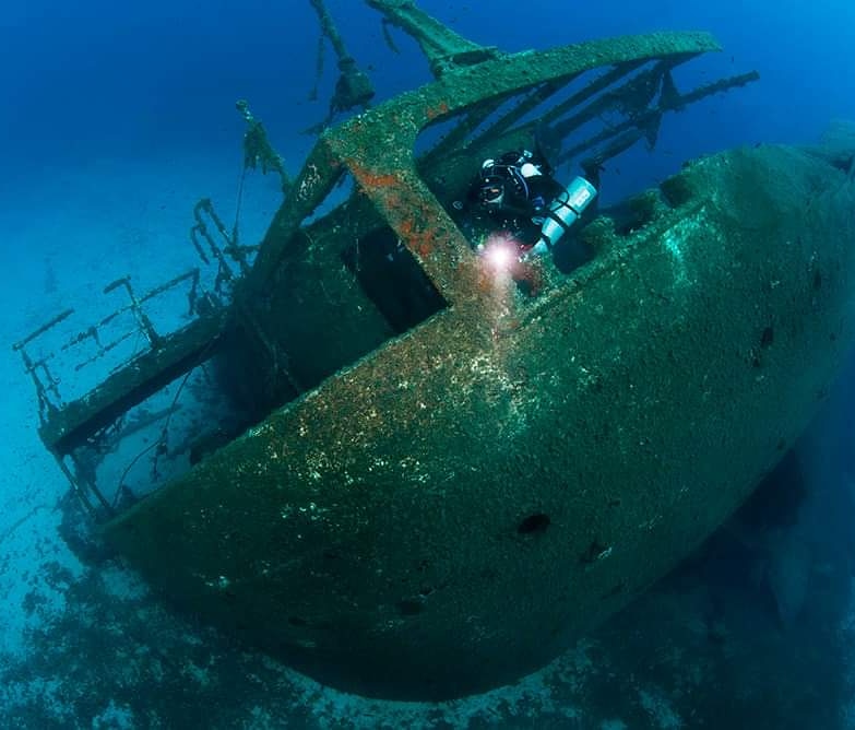A technical diver explores the stern of a sunken ship in Greece