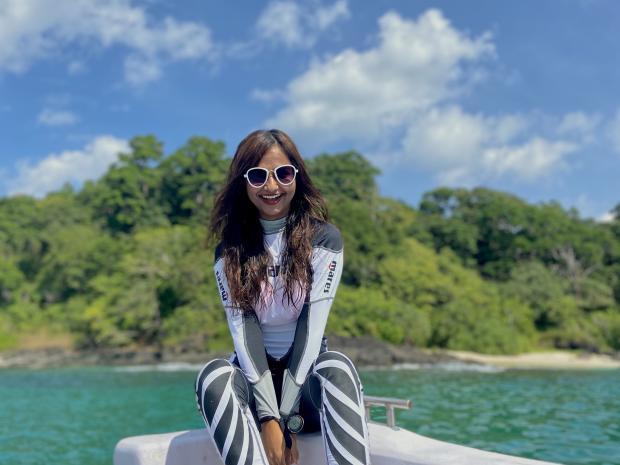 PADI AmbassaDiver Sharanya Iyer sits on the side of a boat in the tropics