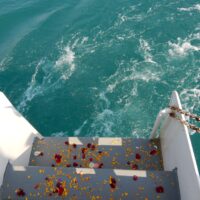 Flower petals scattered down the back steps of a boat loading to the ocean for a memorial