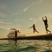 two women jump off a dock into the sea in Curacao