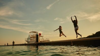 two women jump off a dock into the sea in Curacao