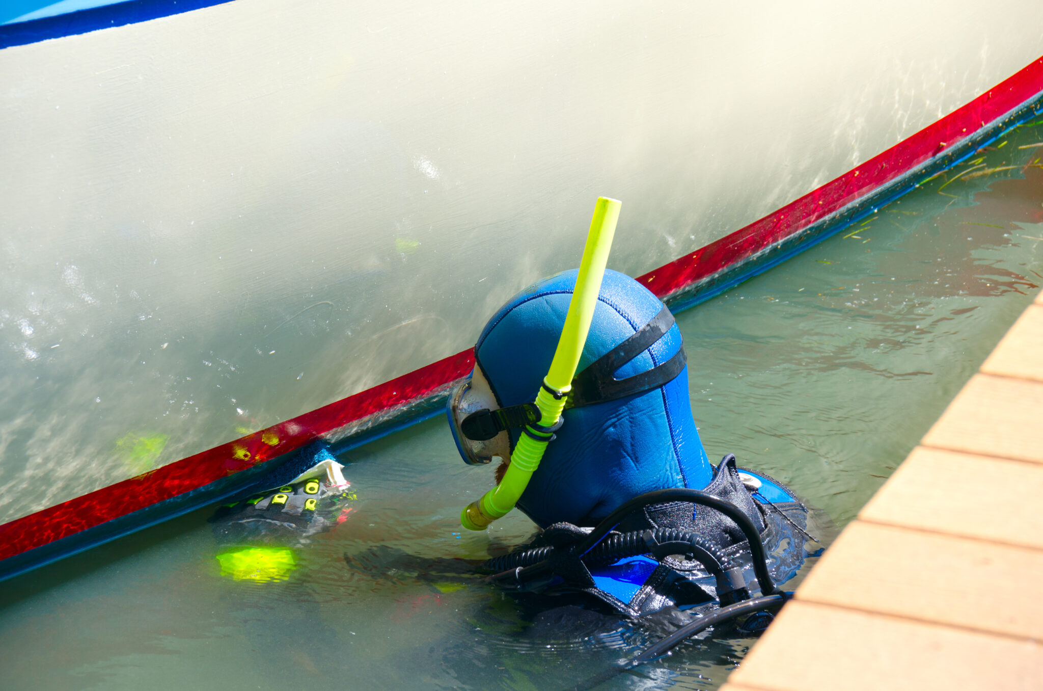 A diver cleans the hull of a boat with a brush