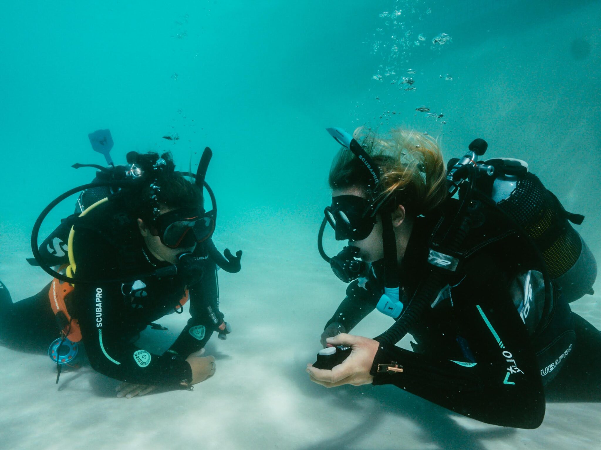 two scuba divers practice their skills underwater in a swimming pool