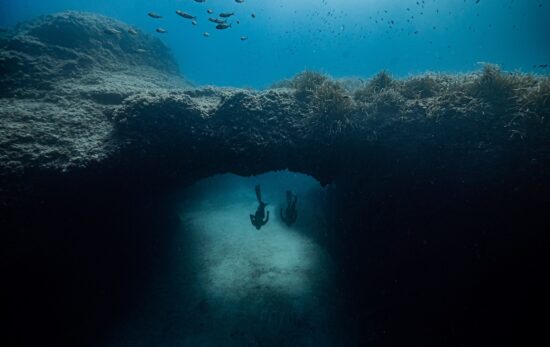 two divers go under an underwater arch