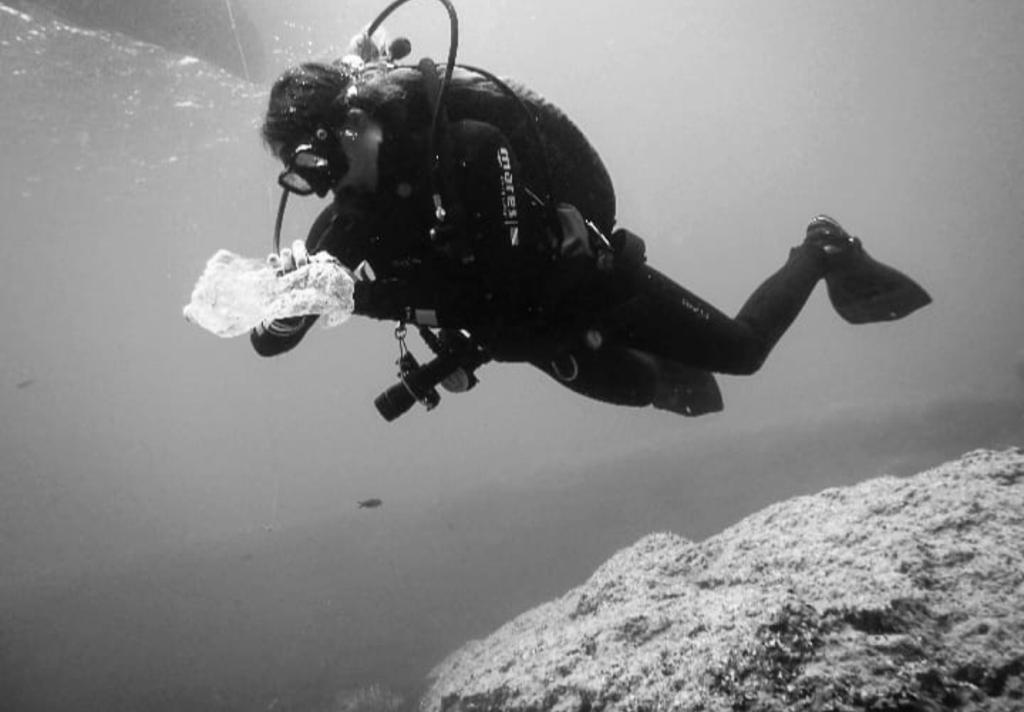 A diver holds debris picked up in an ocean cleanup dive.