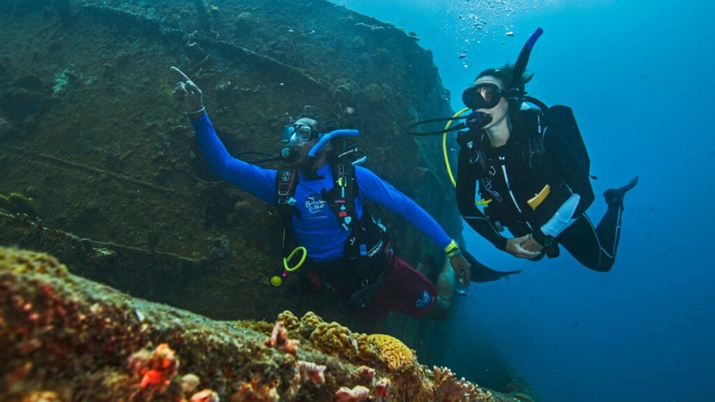 two divers navigating next to a shipwreck