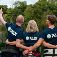 Three scuba diving friends and diving buddies cheering and celebrating after a dive at the inland site at Vobster, UK