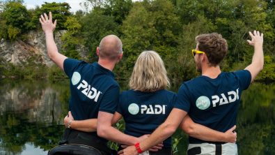 Three scuba diving friends and diving buddies cheering and celebrating after a dive at the inland site at Vobster, UK
