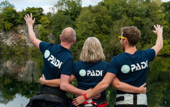 Three scuba diving friends and diving buddies cheering and celebrating after a dive at the inland site at Vobster, UK