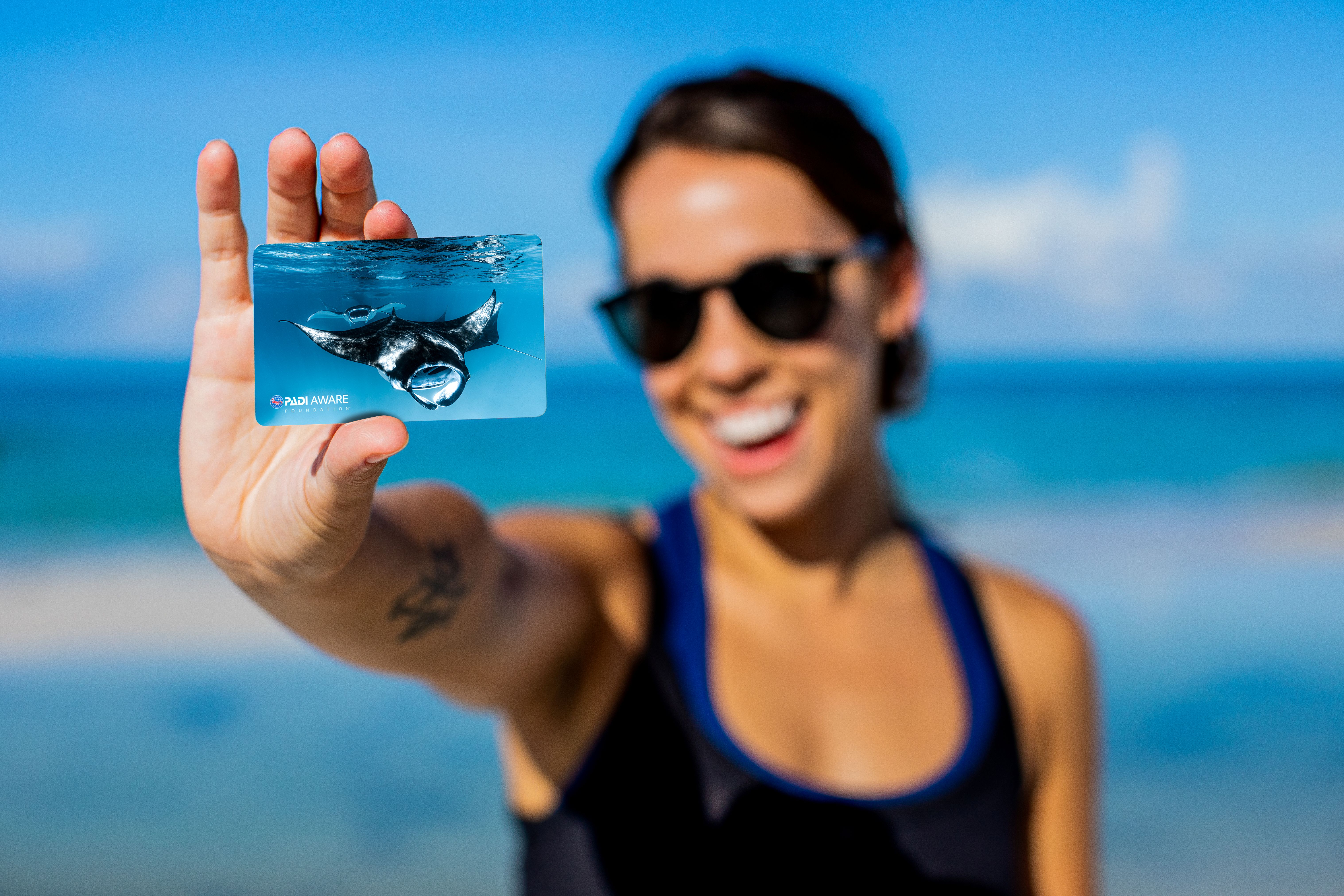 A female diver holding up a certification with a manta on it