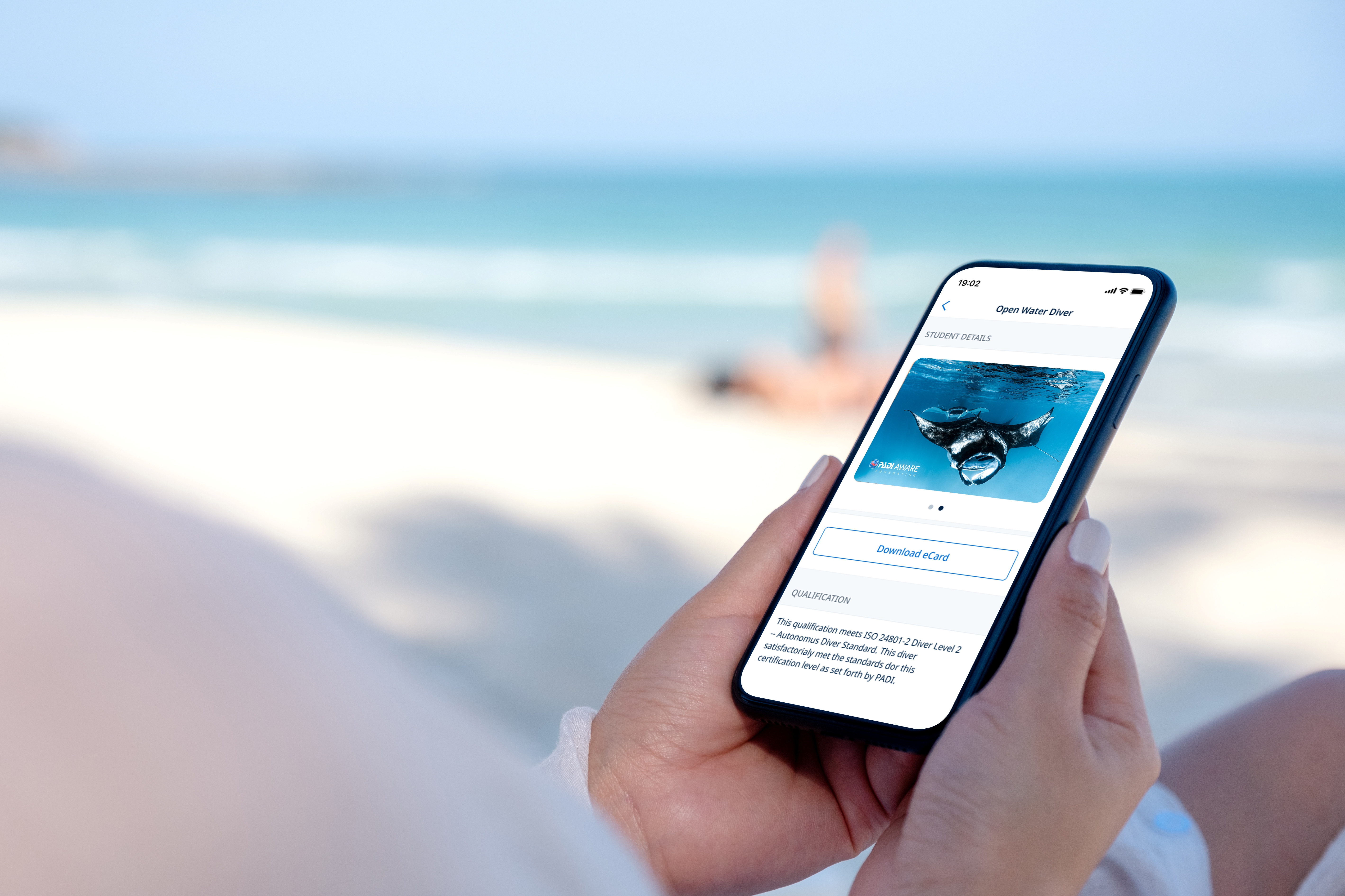 Hands holding a mobile phone with an app showing the Manta certification card on it