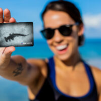 A female diver holding up a certification with a hammerhead on it
