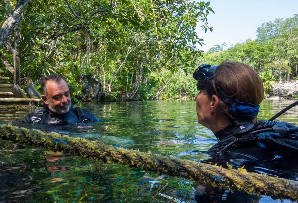 A diver and her instructor float in water before beginning her open water certification.