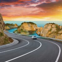 highway landscape at colorful sunset. road view on mediterranean coast of spain. coastal road landscape beautiful nature scenery. car driving on mountain road by the sea. summer vacation on the beach.