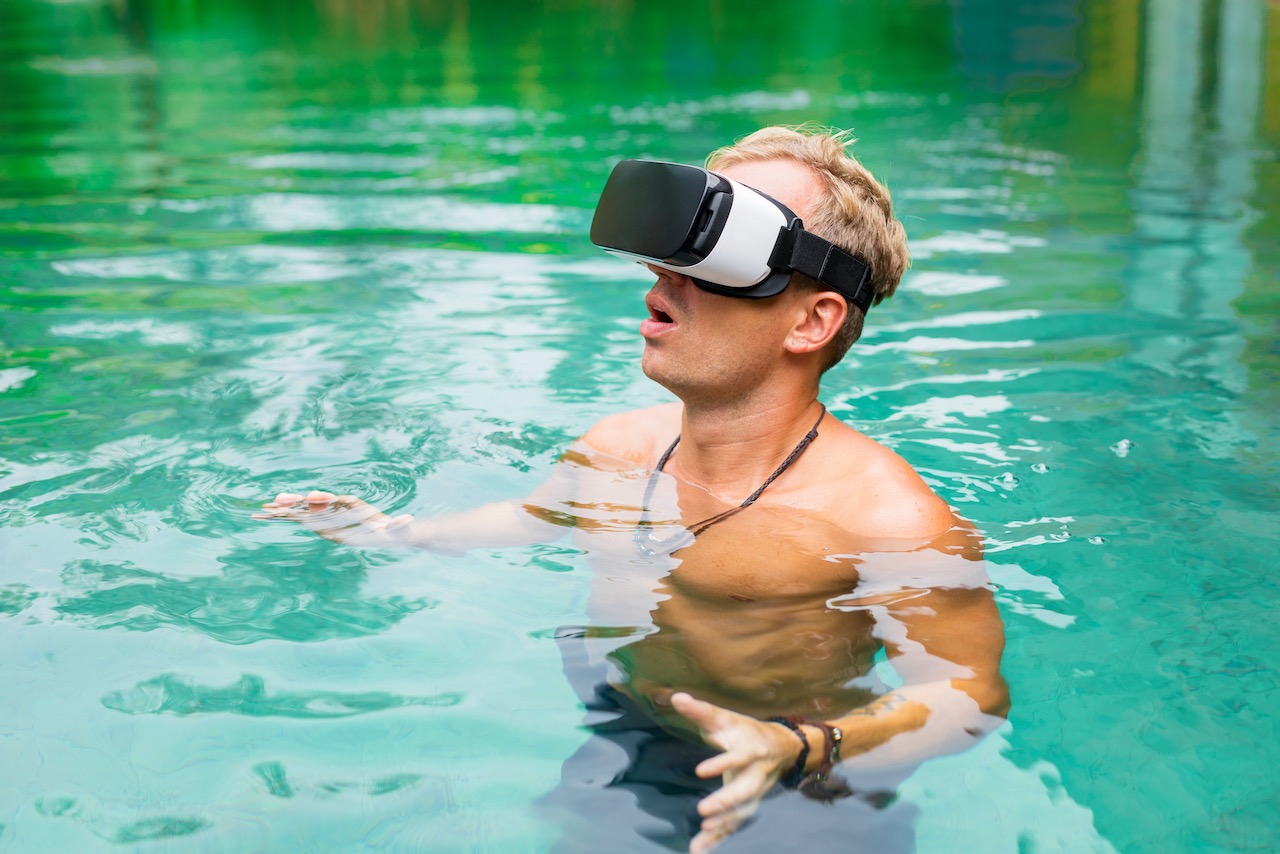 A man wears a VR headset while in a swimming pool