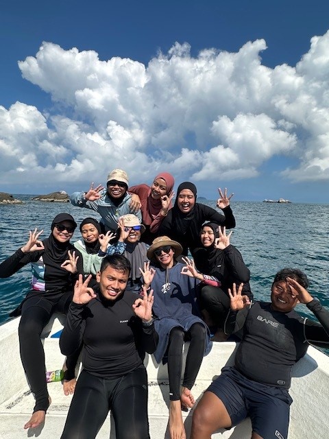 Group photo of divers at the bow of a boat making OK sign