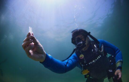 A male scuba diver collects plastic while scuba diving in Mexico