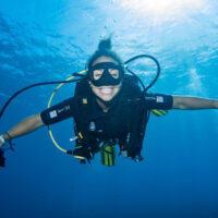 Enjoy a gift of experience - Woman diver smiling at the camera underwater