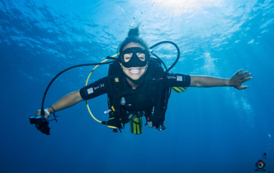 Enjoy a gift of experience - Woman diver smiling at the camera underwater