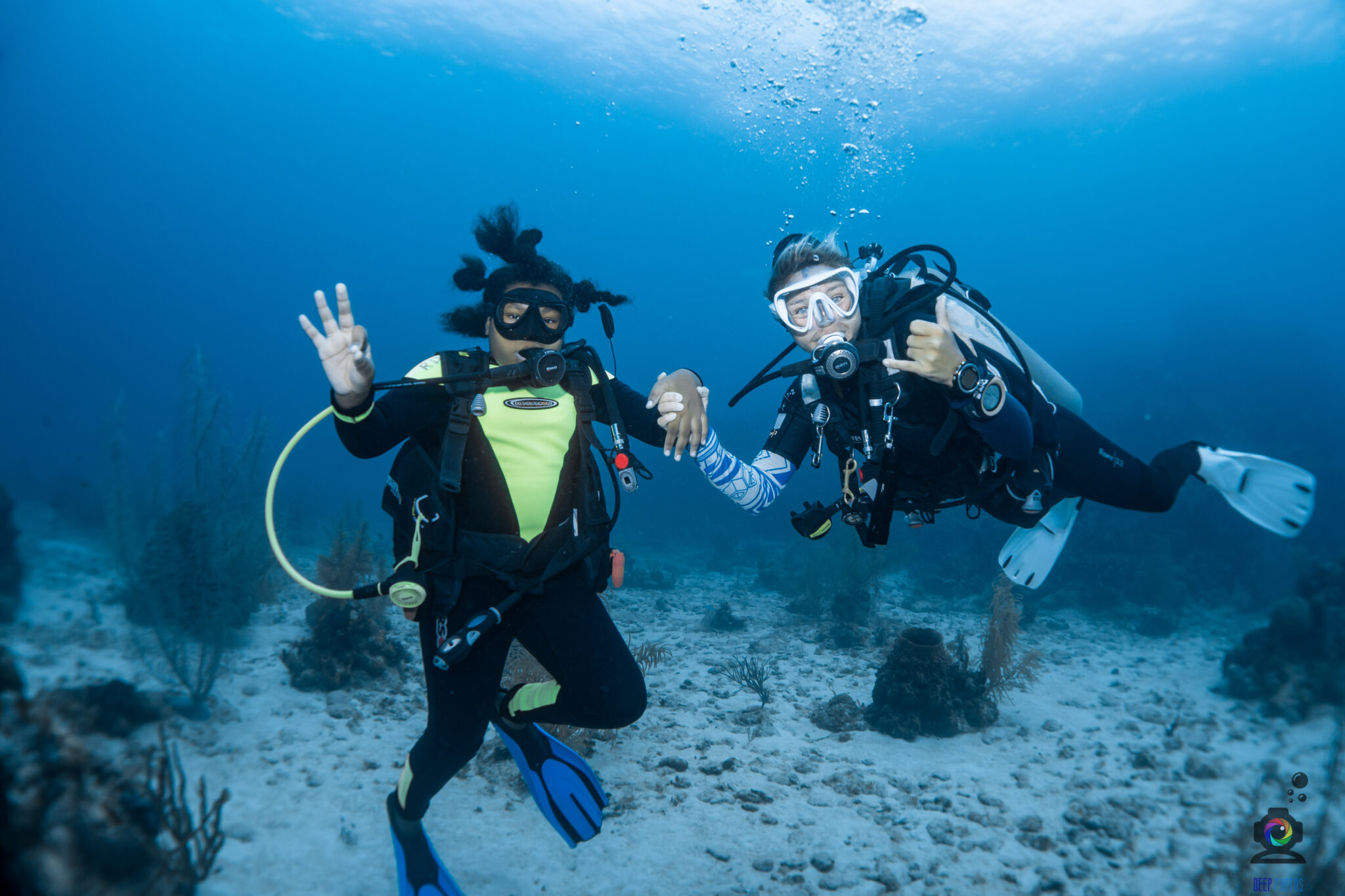 Woman dive leader holding hands with a young diver underwater