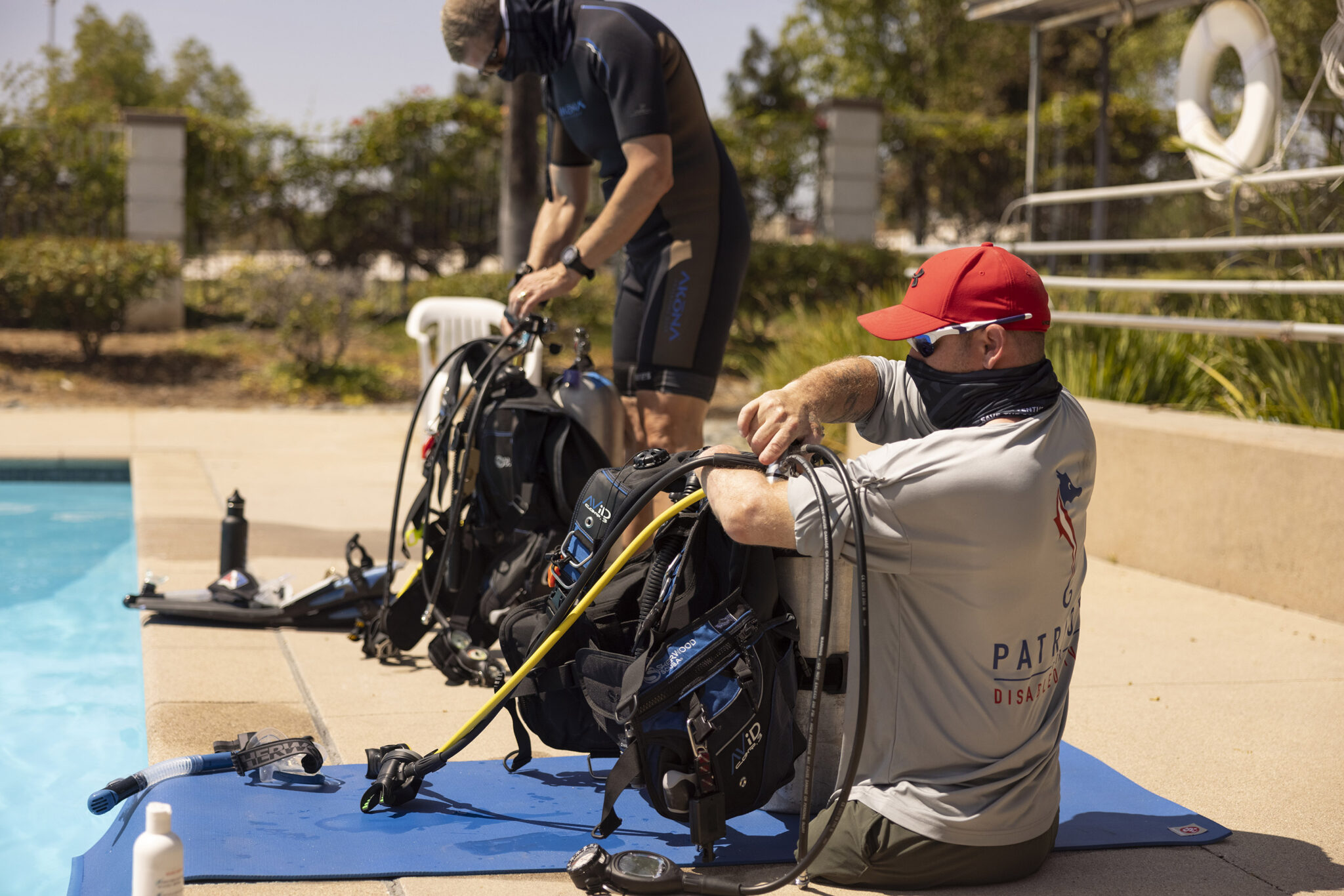 an adaptive diver sets up his scuba gear next to a swimming pool