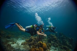 Two PADI Enriched Air Divers swim along a coral reef in Curacao