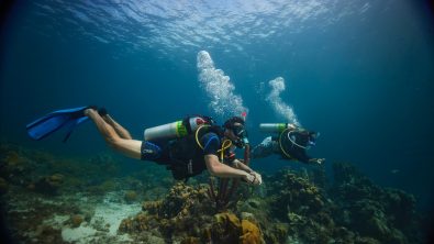 Two PADI Enriched Air Divers swim along a coral reef in Curacao