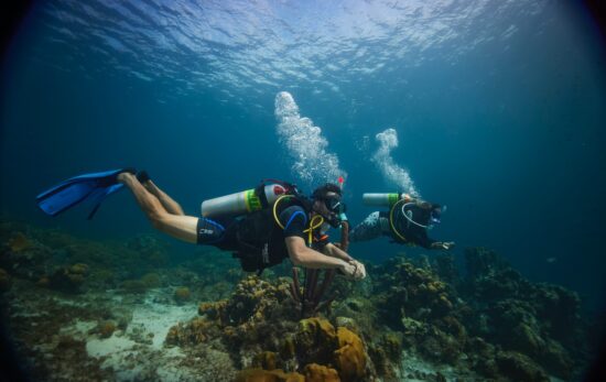 Two PADI Enriched Air Divers swim along a coral reef in Curacao