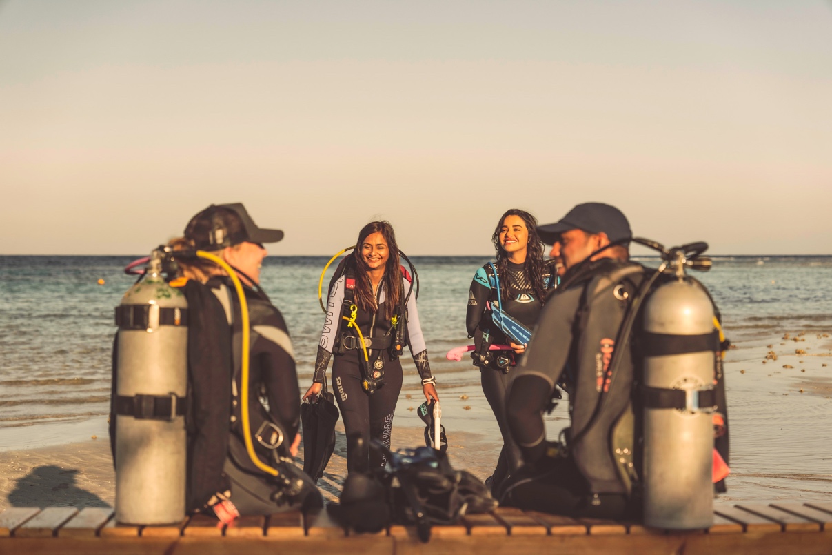 A group of four new Open Water Divers who are part of a local PADI dive club and are about to go diving together in the ocean