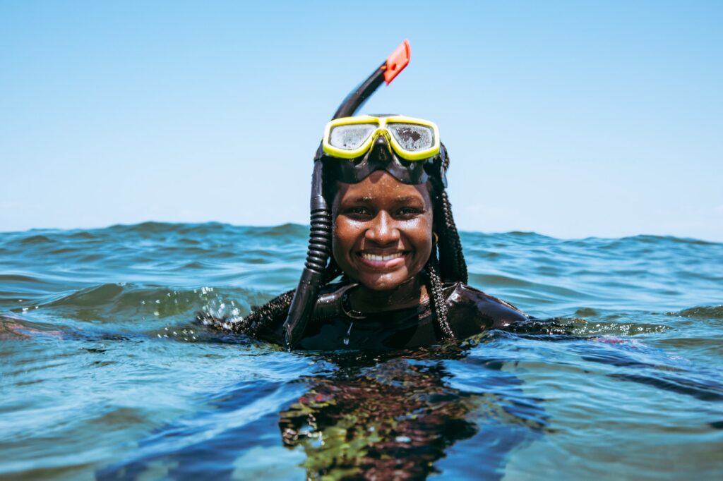 Aida Magaña from Panama floats in the water with a mask and snorkel above her head