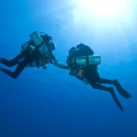 two tec divers from below with sun above