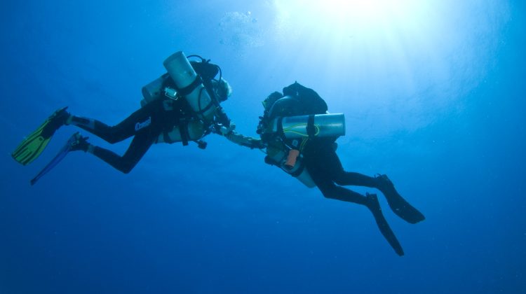 two tec divers from below with sun above