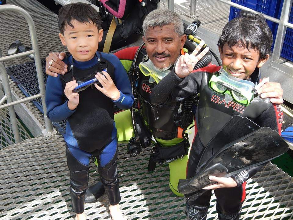 Syed Abd Raman poses with two children, who are student divers and snorkelers