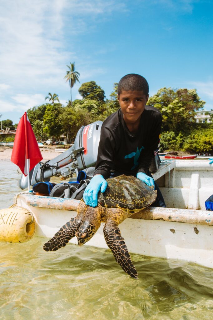Idiel Guitierrez holds a sea turtle ready for release on the side of a boat