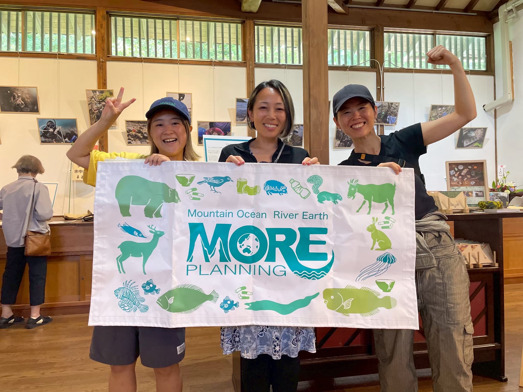 Ambassadiver Yumi Shirai in a classroom holding a sign with two other women for MORE school for conservation