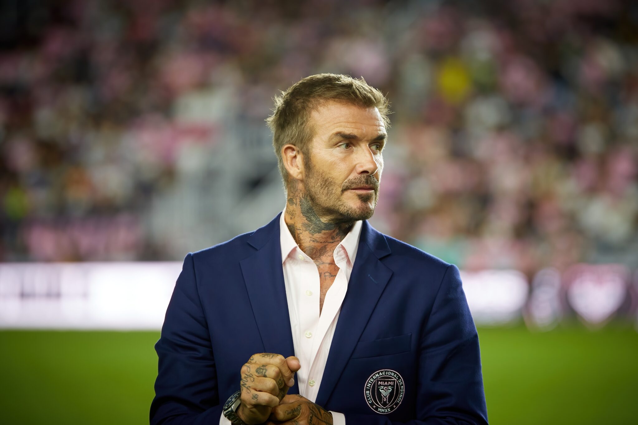 David Beckham walks on a football field in a suit