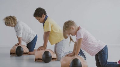 three children learn CPR using dummies