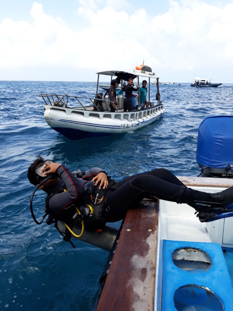 A diver does a backroll entry off a dive boat.