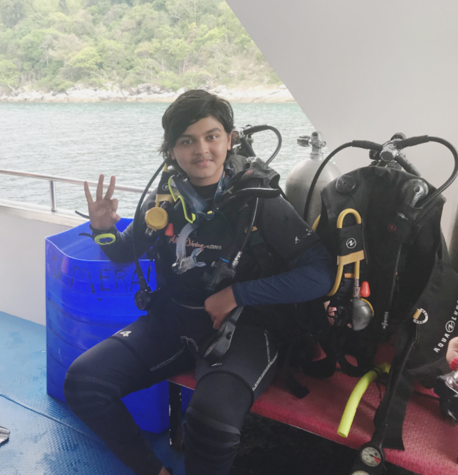 A diver waves to the camera while getting kitted up in gear.