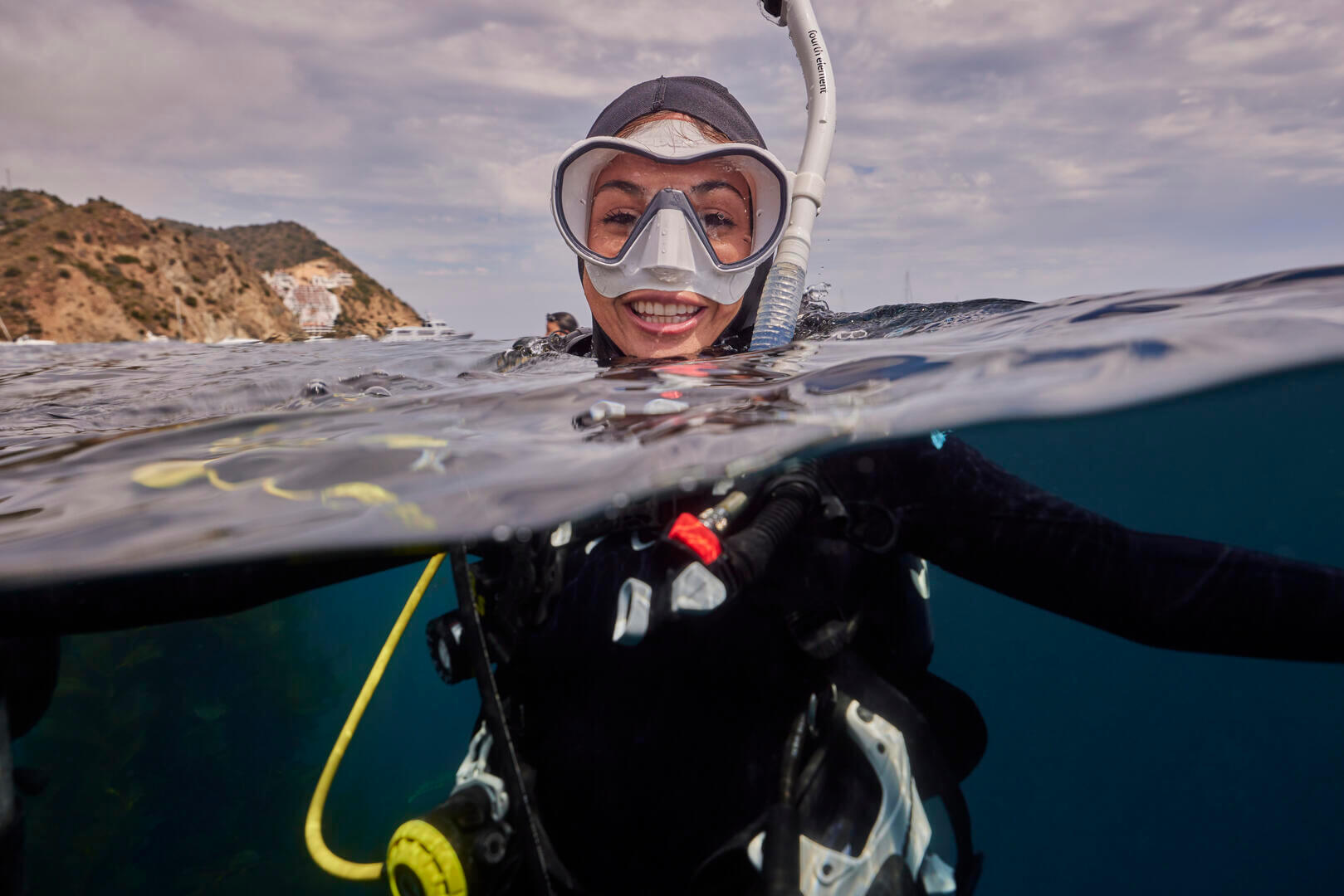 an open water diver smiles for the camera at the surface