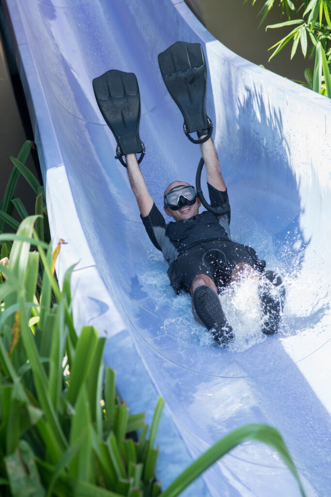 Diver with fins on hands, sliding in a water slide