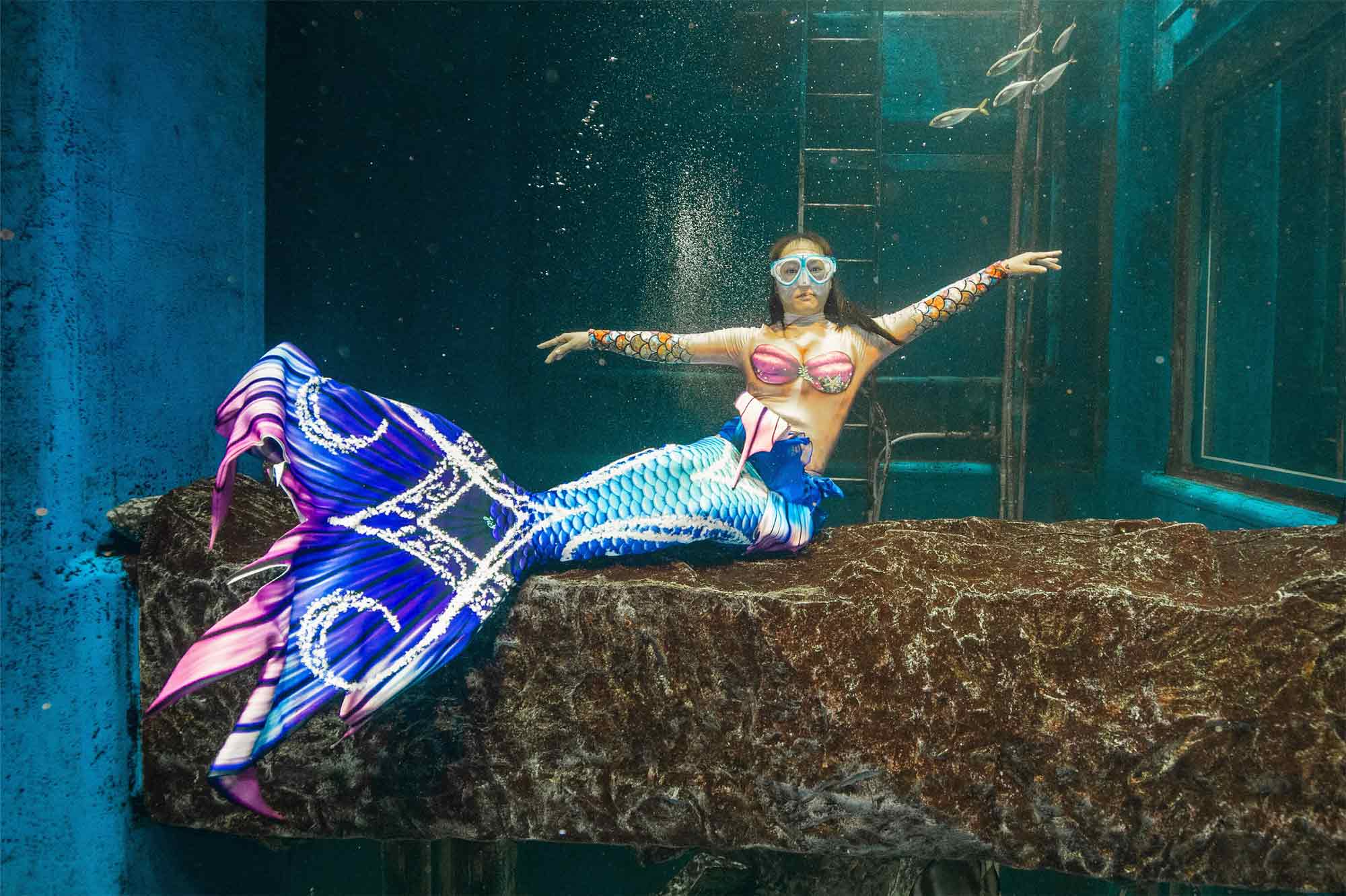 a mermaid posing with arms open under the water