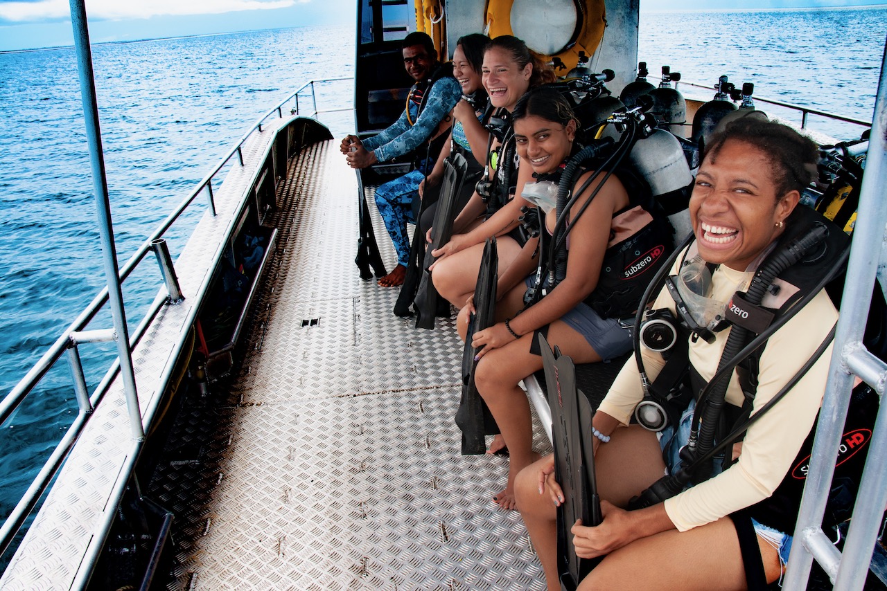 A group of divers on a boat in Fiji on their way to dive the Great Sea Reef