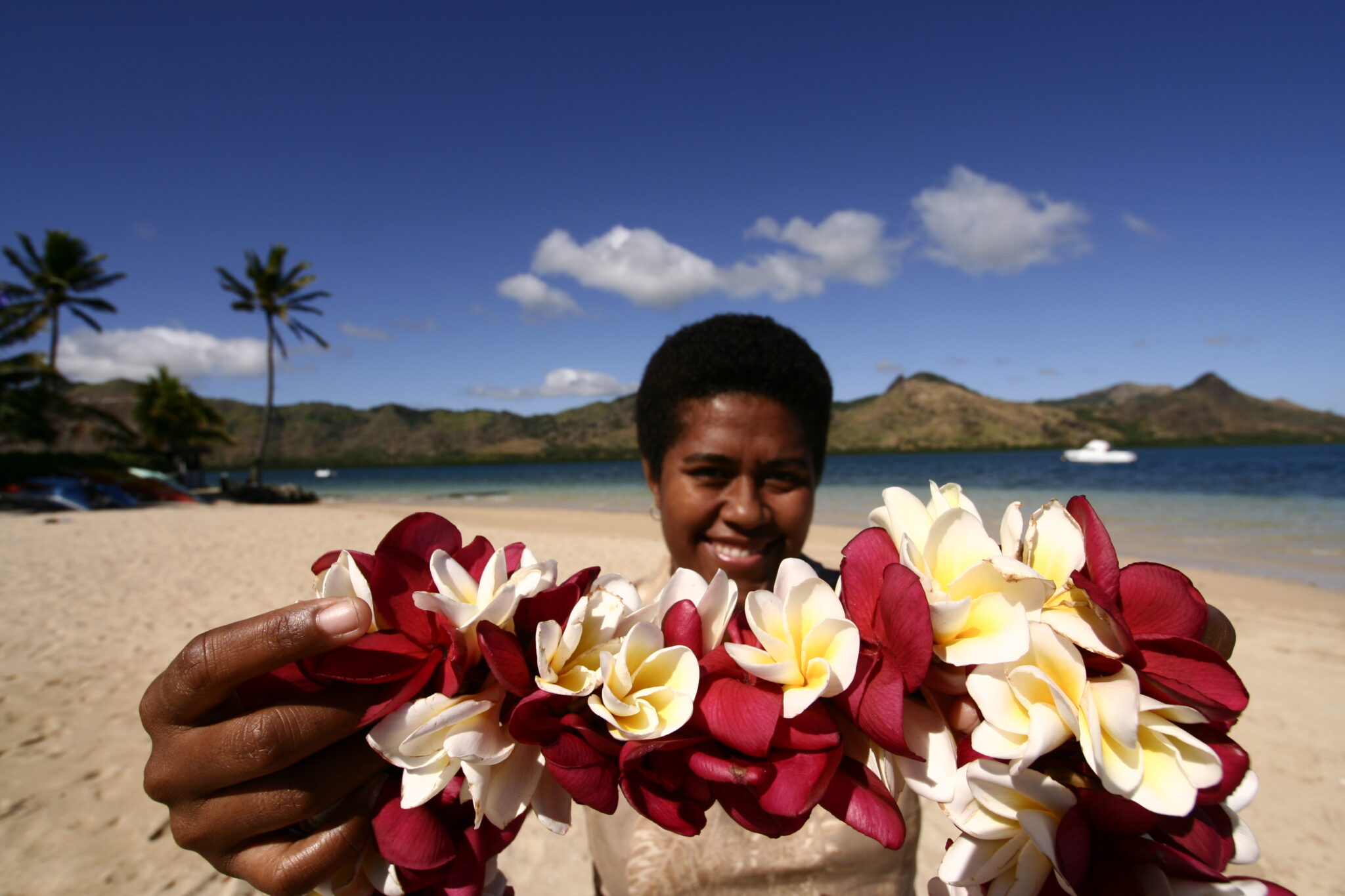 A Fijian holds up a flower necklace as a welcome symbol